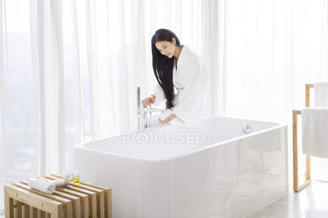 Mujer china llenando la bañera con agua - foto de stock