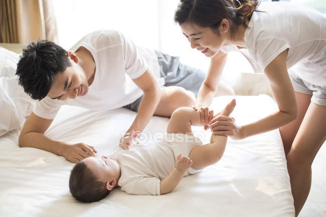 Китайская семья с маленьким мальчиком, отдыхающим на кровати — стоковое фото