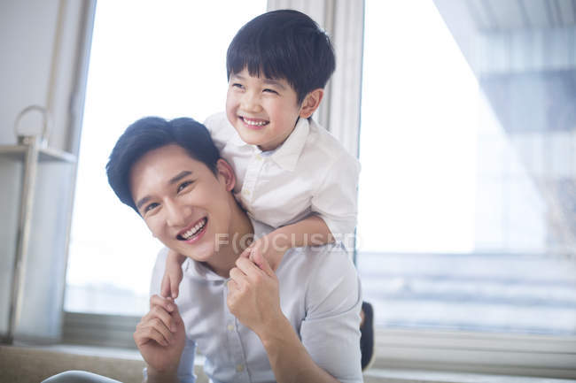 Menino chinês abraçando pai na sala de estar — Fotografia de Stock