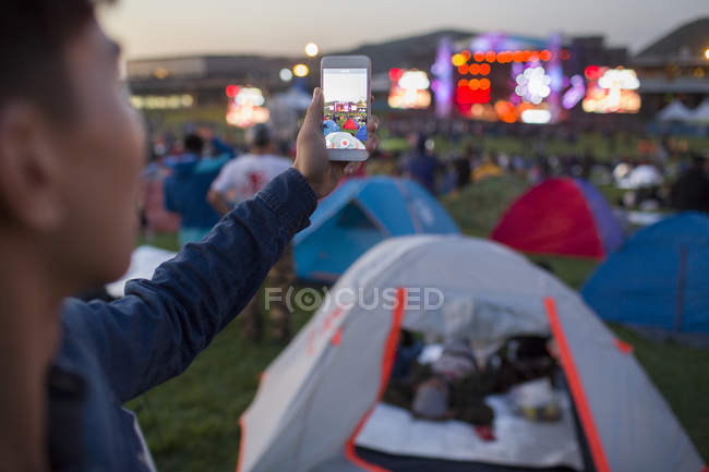 Chinese man taking photos with smartphone at music festival — Stock Photo