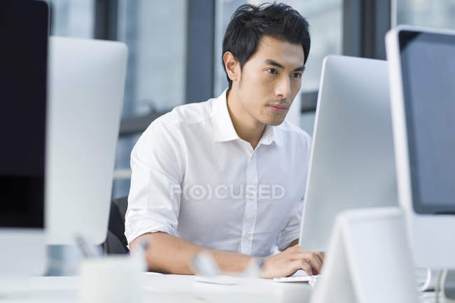 Китайский бизнесмен пользуется компьютером в офисе — стоковое фото