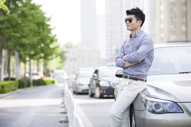 Chinese man leaning on car — Stock Photo
