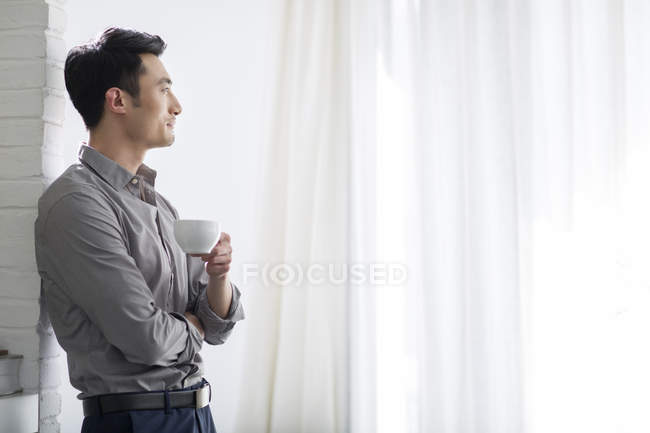 Asian businessman drinking coffee in office — Stock Photo