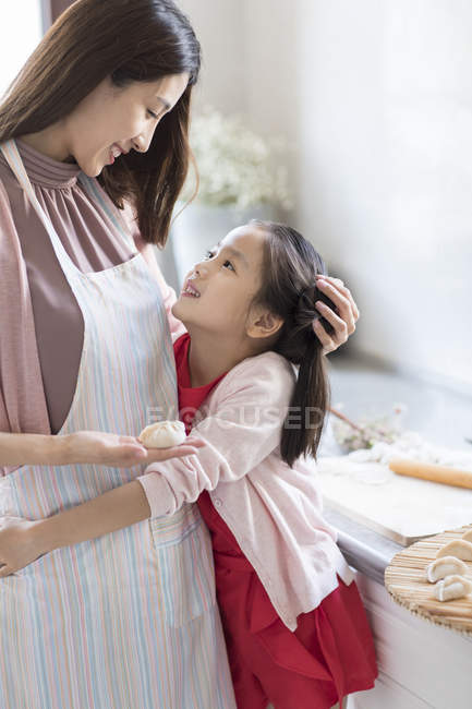 Chinese mother and daughter embracing while making dumplings — Stock Photo