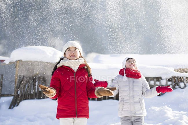 Chinese girls catching falling snow outdoors — Stock Photo