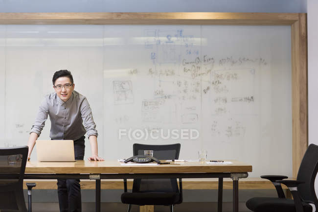 Chinese man using standing with laptop in board room — Stock Photo
