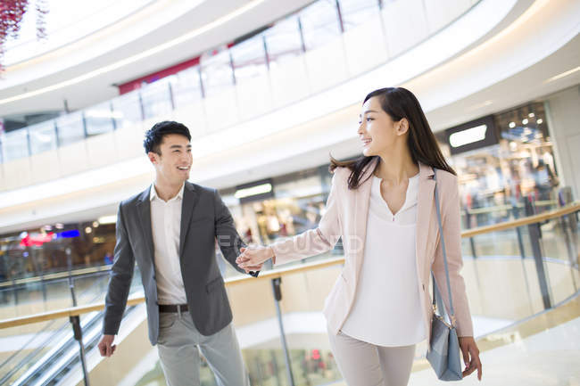 Chinese couple walking in shopping mall — Stock Photo