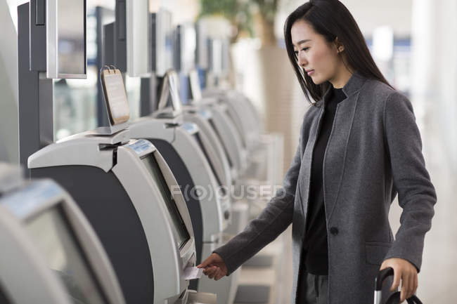 Mulher asiática usando a máquina de bilhetes no aeroporto — Fotografia de Stock