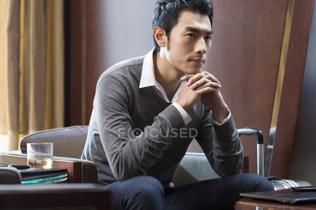 Portrait of pensive Chinese businessman in hotel room — Stock Photo