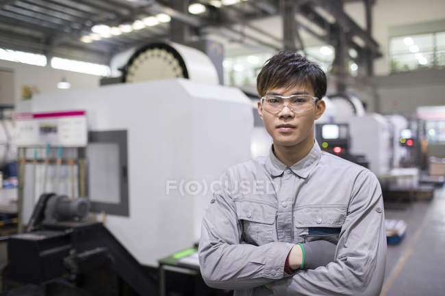 Уверенный китайский инженер со скрещенным на заводе оружием — стоковое фото