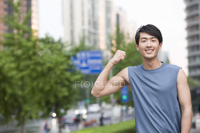 Chinês homem flexionando músculos na rua — Fotografia de Stock
