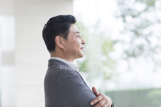 Asian businessman standing with arms folded — Stock Photo