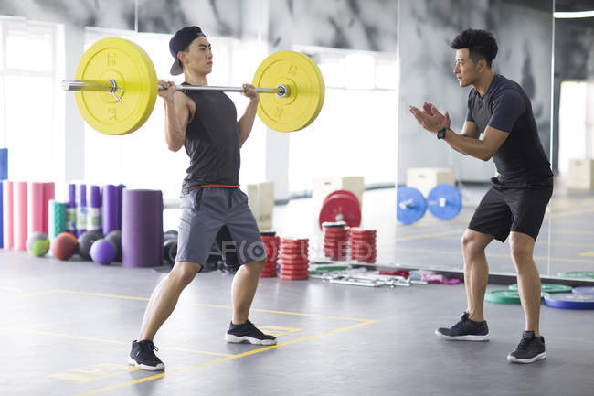 Азиатский мужчина работает с тренером в тренажерном зале — стоковое фото