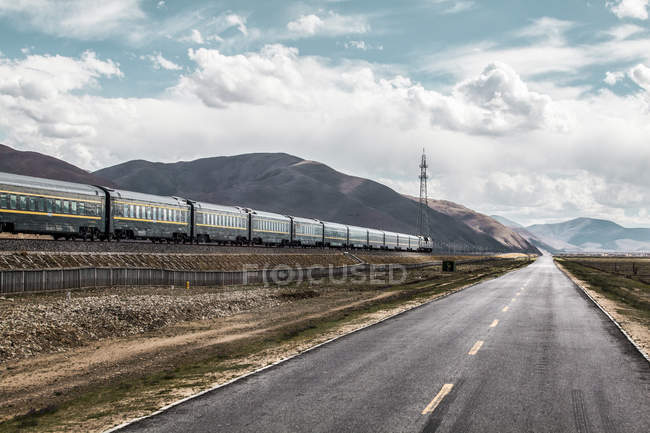 Train at railway going along highway in Tibet, China — Stock Photo
