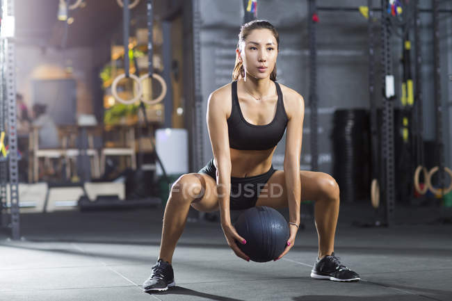 Chinese woman exercising with medicine ball at gym — Stock Photo