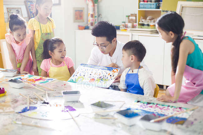Chinese children sitting in art class with teacher — Stock Photo