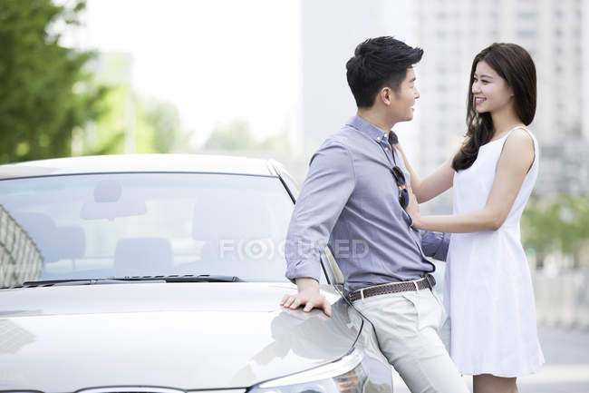 Chinese couple leaning on car — Stock Photo