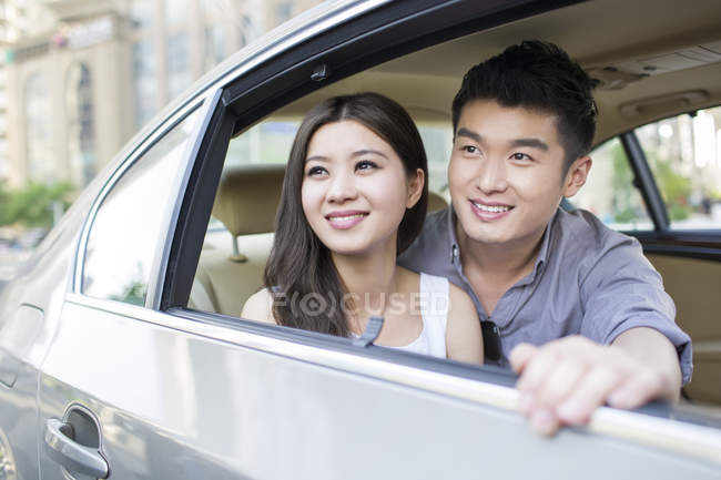 Casal chinês sentado no banco de trás do carro — Fotografia de Stock
