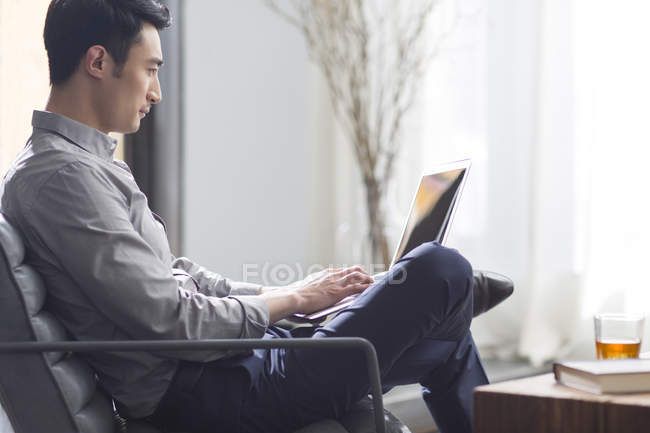 Молодой человек, работающий с ноутбуком в офисе — стоковое фото