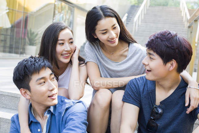 chinese-friends-talking-together-on-stairs-cheerful-male-stock