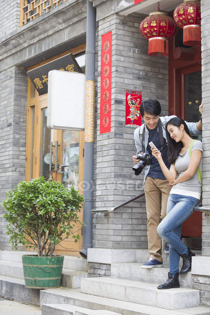 Chinese couple holding smartphone and camera — Stock Photo