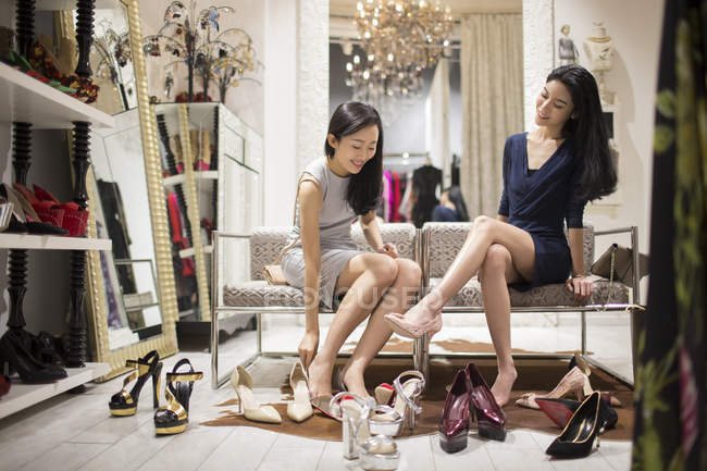 Amigas chinesas experimentando sapatos na loja — Fotografia de Stock