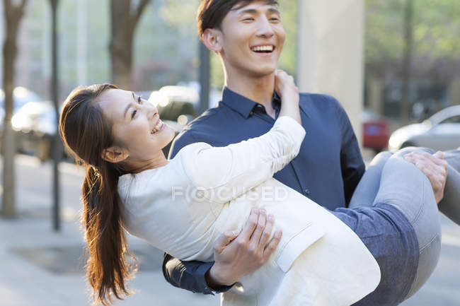 Китаец с подружкой на руках на улице — стоковое фото