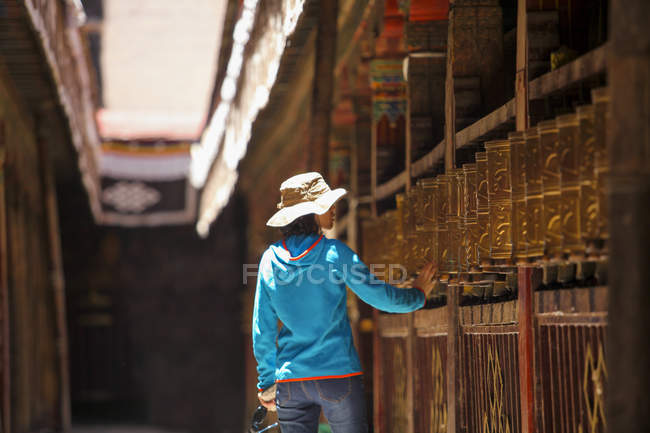 Rear view of tourist touching prayer wheels in Jokhang Temple in Tibet — Stock Photo