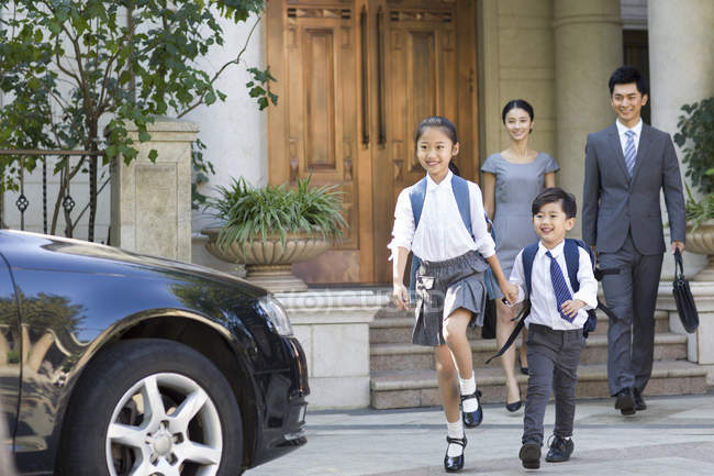 Китайські діти, тримаючись за руки і ходьба при батьками дивляться у фоновому режимі — стокове фото