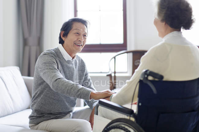 Senior Chinese man taking care of senior woman in wheelchair — Stock Photo
