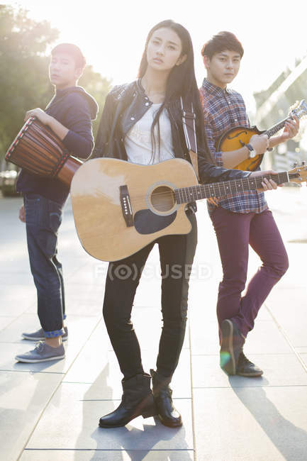 Amis chinois posant avec des instruments de musique dans la rue — Photo de stock