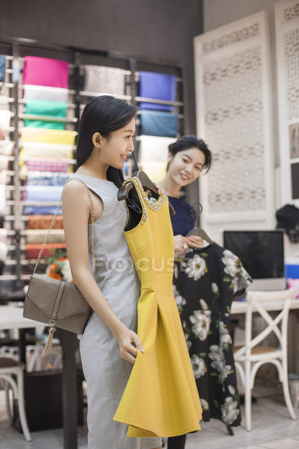 Propietario de tienda de ropa china ayudando al cliente a elegir vestidos - foto de stock
