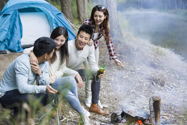 Amigos chineses sentados ao lado da fogueira na floresta — Fotografia de Stock
