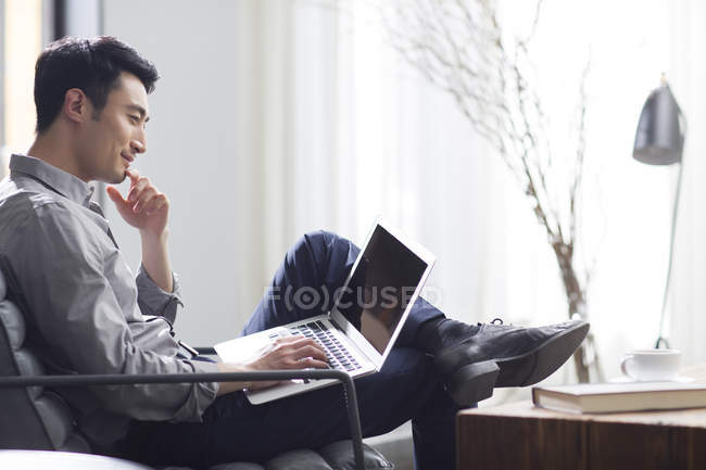 Азиатский человек работает с ноутбуком в офисе — стоковое фото