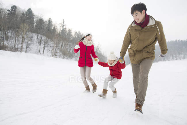 Família chinesa com filha correndo na neve — Fotografia de Stock