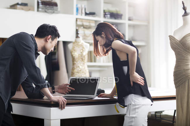 Asian fashion designers working in studio with laptop — Stock Photo