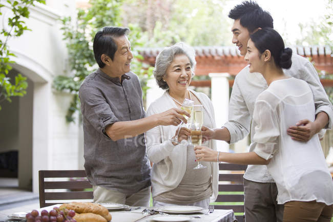 Família chinesa feliz comemorando com champanhe ao ar livre — Fotografia de Stock