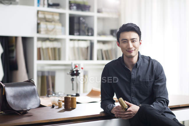 Asiático macho artesano sentado en estudio - foto de stock