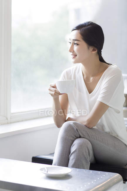 Mujer china bebiendo café en la cafetería - foto de stock