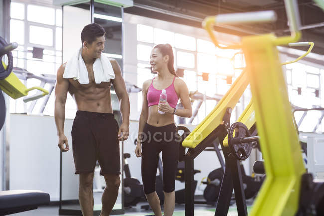 Chinese couple resting at gym  with towel and bottle of water — Stock Photo