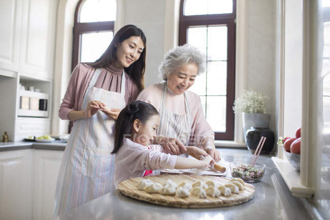 Chinese family making dumplings in kitchen — Stock Photo