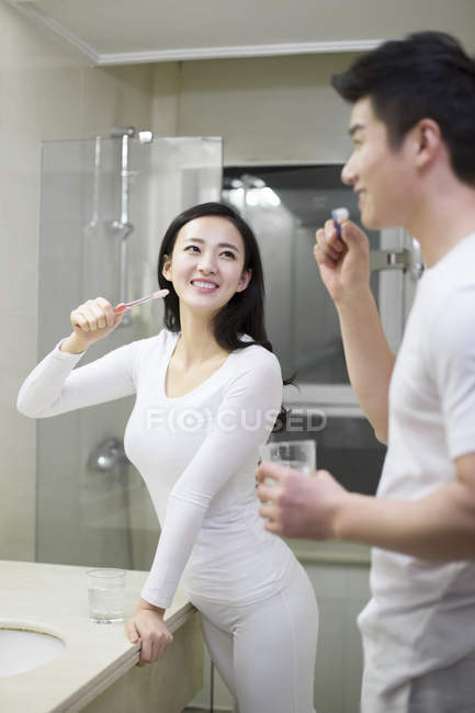 Asian couple brushing teeth in bathroom — Stock Photo