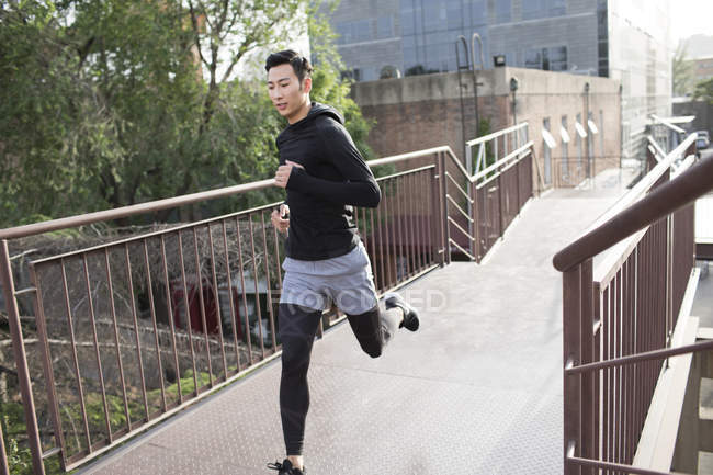 Homem chinês correndo na ponte na cidade — Fotografia de Stock