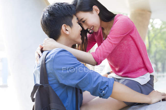 Casal chinês sentado cara a cara e abraçando na rua — Fotografia de Stock