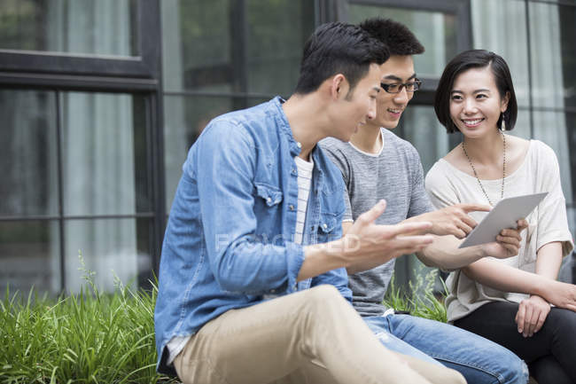 Chinese casual business team talking with digital tablet in city — Stock Photo