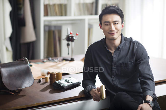 Asiático macho artesano sentado en estudio - foto de stock