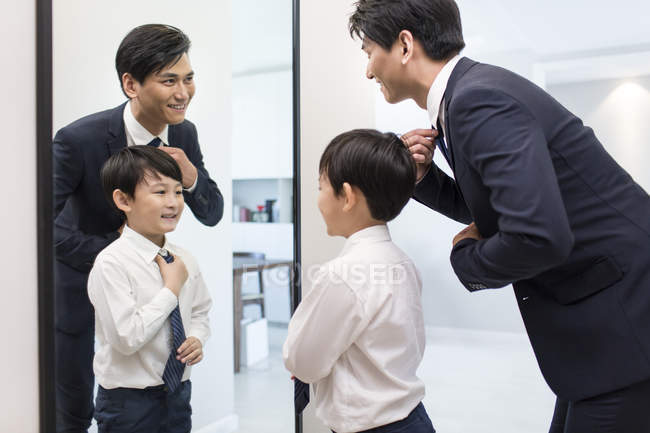 Père et fils chinois ajustant les liens le matin — Photo de stock