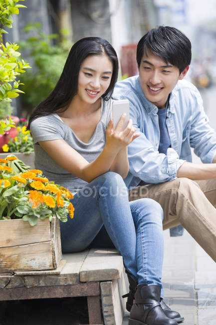 Chinese couple using smartphone on street — Stock Photo
