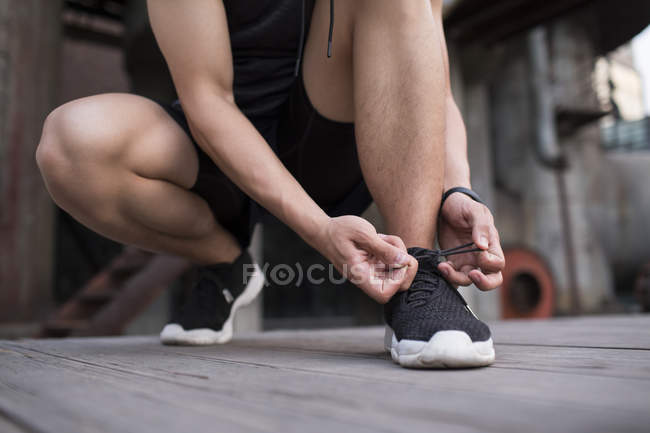 Atleta masculino amarrando laço sapato — Fotografia de Stock