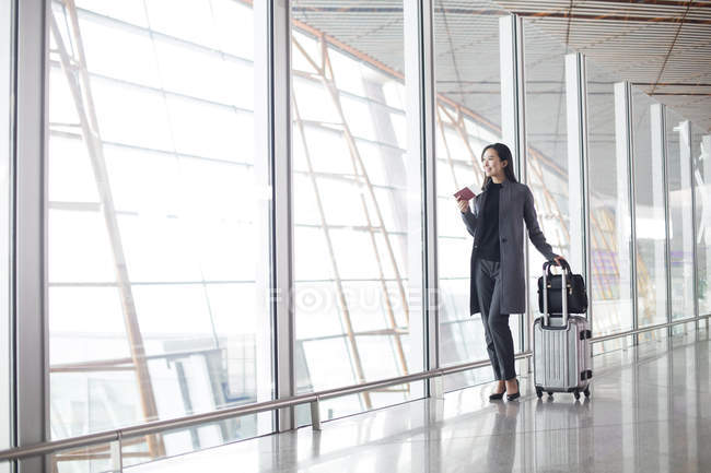 Mulher asiática de pé com bagagem no lobby do aeroporto — Fotografia de Stock